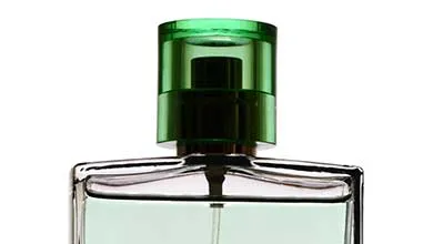 Close-up of a clear perfume bottle with a translucent bright green cap on a white background.
